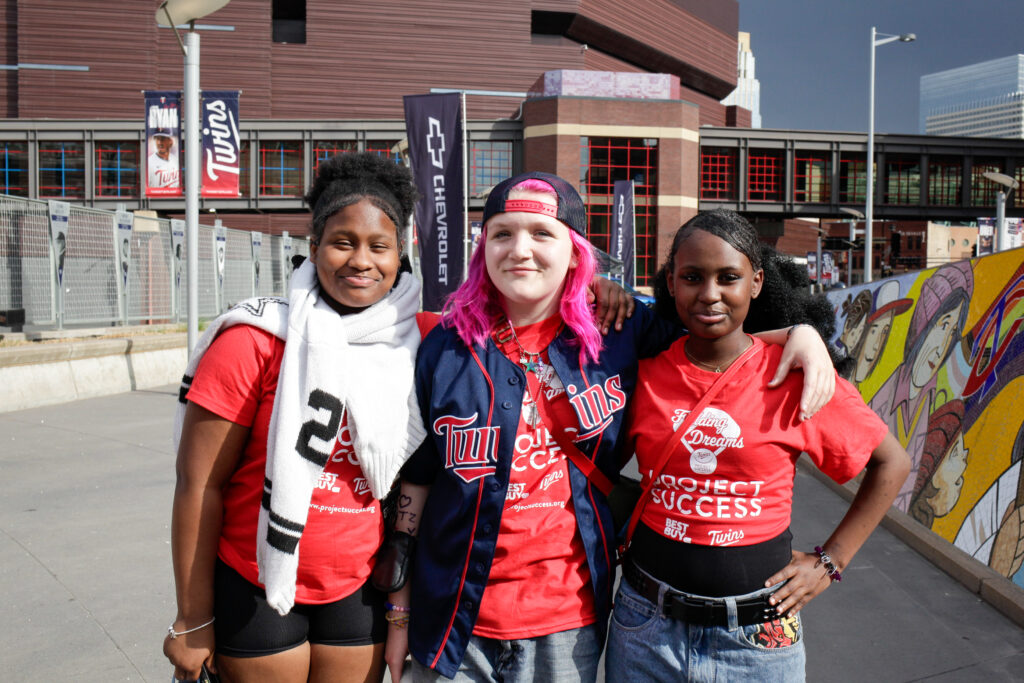 Three students smiling with their arms around each other.