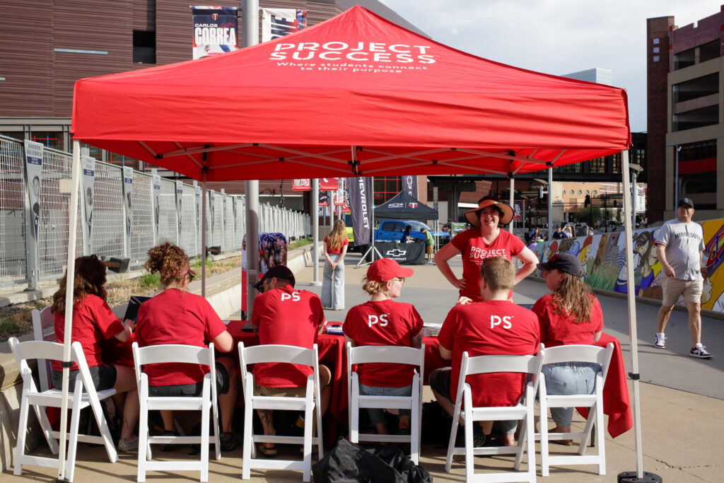 Photo from behind of PS staff members under a Project Success tent for check in.