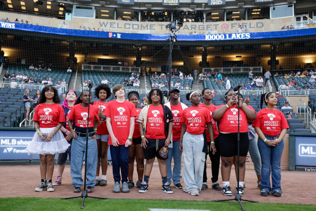 Group of students singing an opening song on the baseball field.