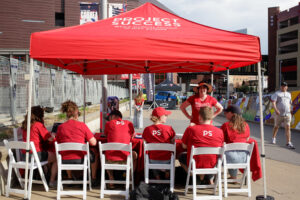Project Success staff in red PS shirts under a pop up tent.