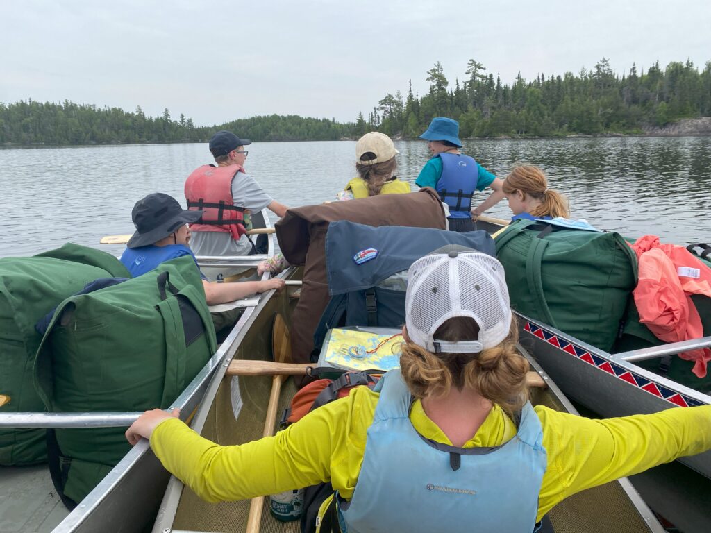 Three canoes being held together by leaders as they navigate in the water.