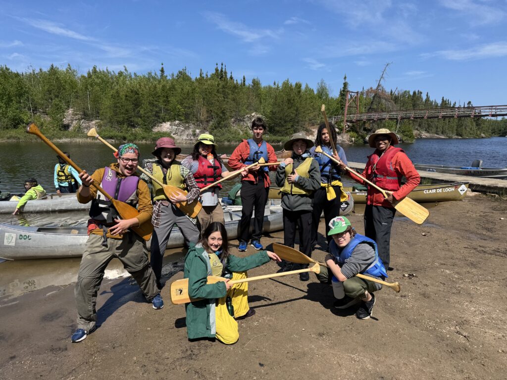 Group of students holding their paddles like guitars and smiling.