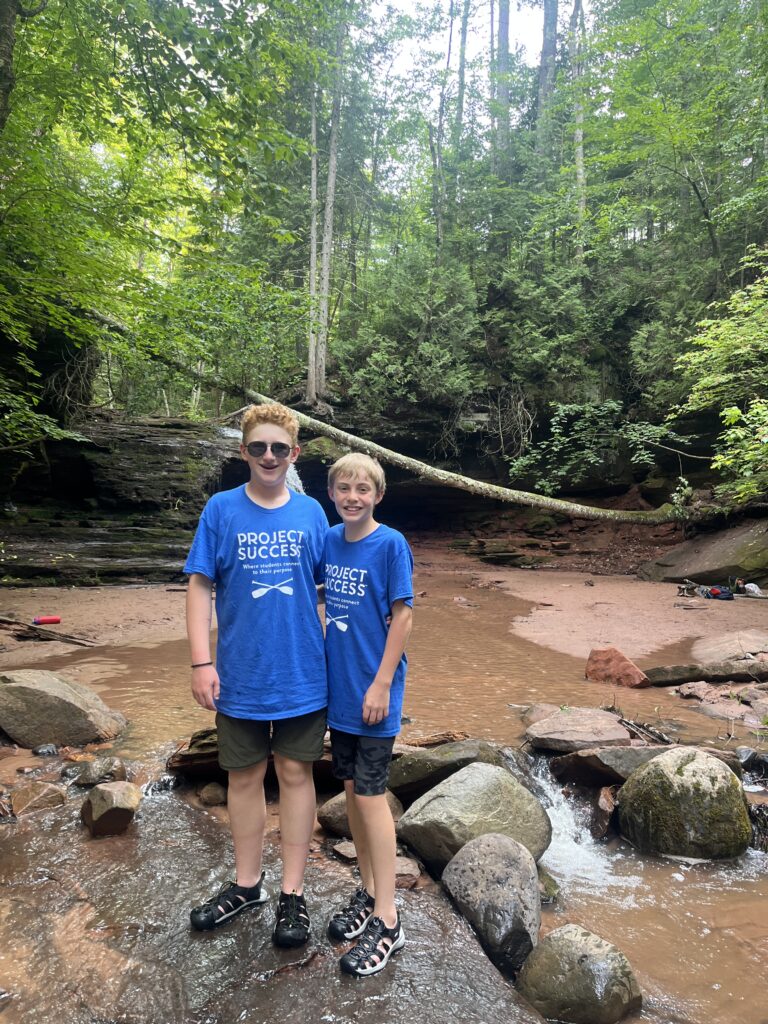 Two students smiling on a hike.