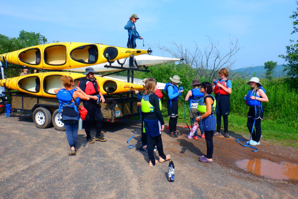 Students smiling in front of their kayaks.