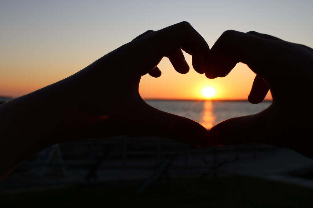Sunset picture of two hands making a heart.