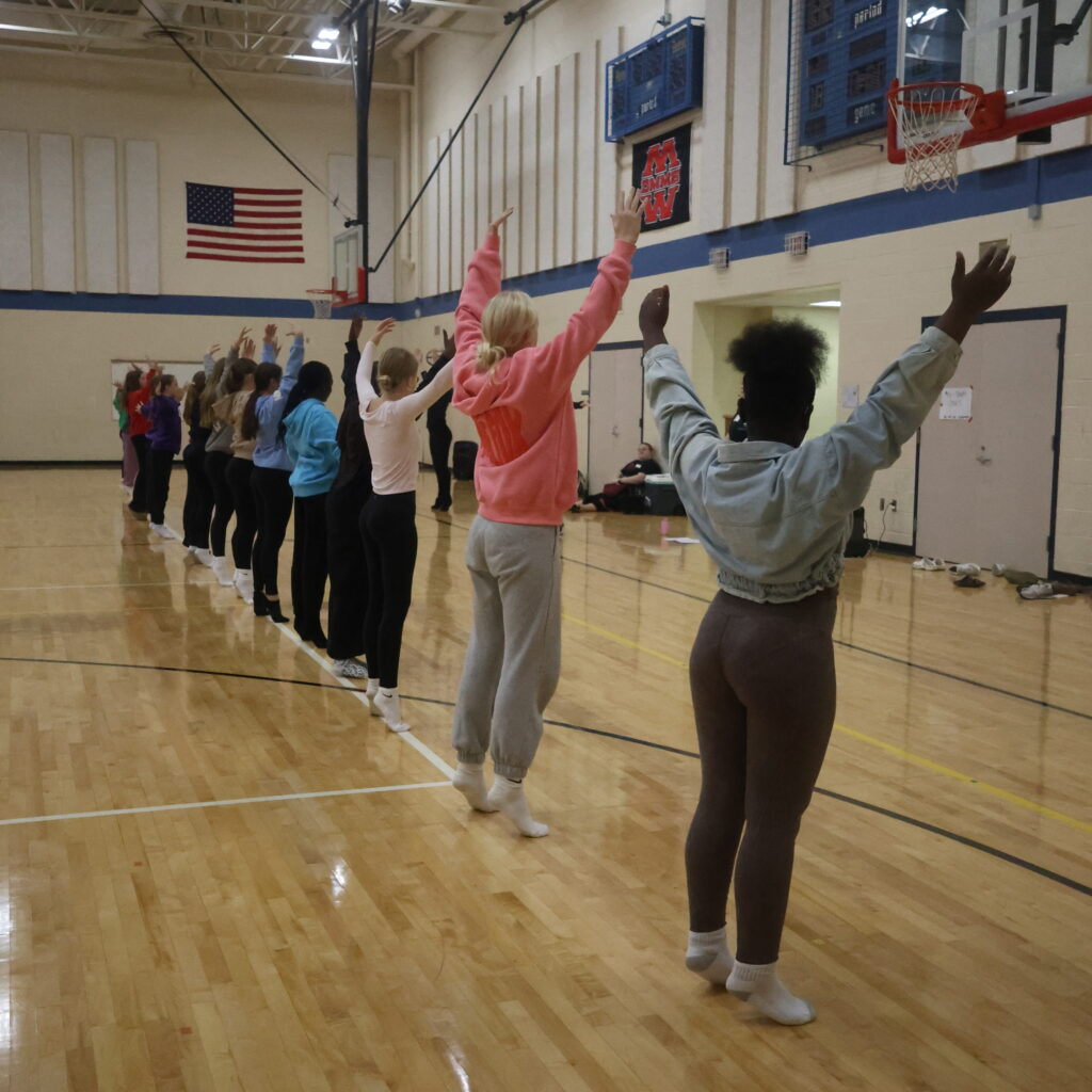 students with their arms up.