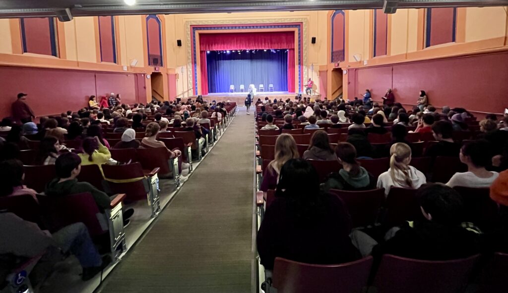 Students watching performance on stage.